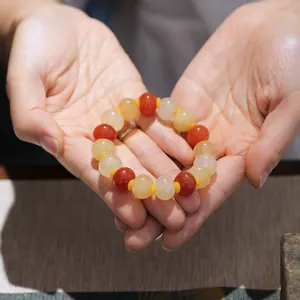 Close-up of ethnic beaded bracelet with red and yellow gemstones held in palms