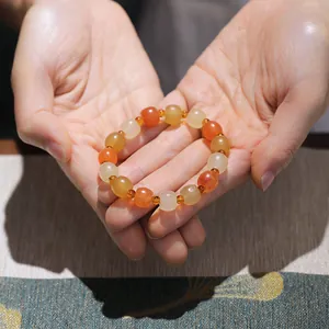 Macro shot of warm-toned gold silk jade beaded bracelet with pumpkin beads held in hands