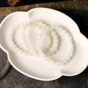 Naturweißes Mondstein-Perlenarmband Set mit blauem Schimmer auf Keramikschale