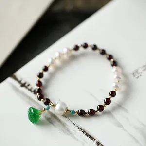 Close-up of garnet beads, freshwater pearls, and an emerald green carved jade pendant