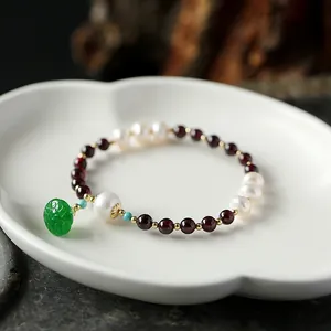 Macro view of garnet beads bracelet with freshwater pearls and green jadeite pendant