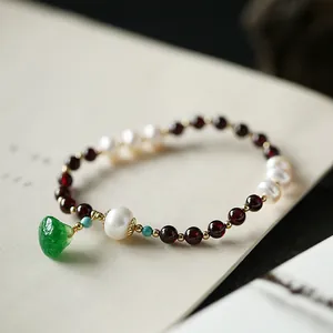 Macro detail of garnet beads and freshwater pearl bracelet with green jade pendant