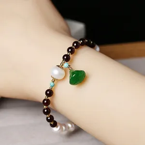 Detail of beaded bracelet with garnet, freshwater pearls, and green jade pendant