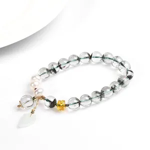 Macro detail of natural green phantom crystal bracelet with pearls and leaf pendant