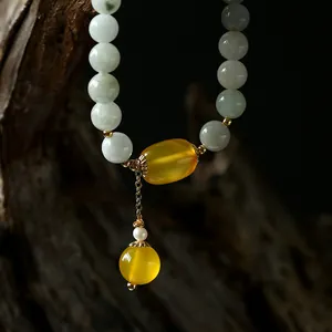 Macro shot of natural green jadeite beaded bracelet with yellow agate and gold tassels