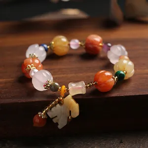 Détail de perles en forme de citrouille avec pendentif en jade sur bois poli