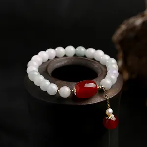 Detail of green jadeite bracelet with red agate barrel bead and 14K gold tassel charm