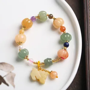 Macro detail of pumpkin-shaped jade beads with a carved rabbit charm on a beaded bracelet