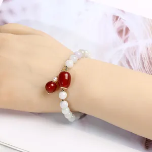 Detail of beaded jadeite bracelet with red agate tassel and pearl on woman's wrist