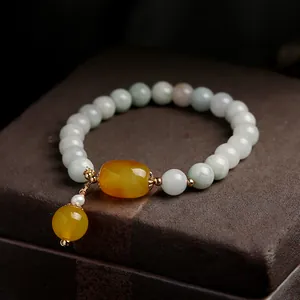 Close-up of green jade bead bracelet with yellow amber pendant on dark jewelry box