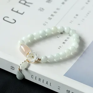 Macro detail of natural jade beads bracelet with shell flower and gold accents
