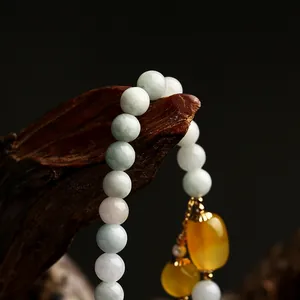 Macro detail of natural jade beads bracelet with yellow agate charms on wood