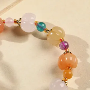 Detailed close-up of multi-colored natural stone beads with pumpkin shapes and gold accents