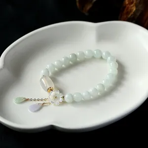 Detailed macro of natural jade bead bracelet with 14K gold shell flower and jade drops