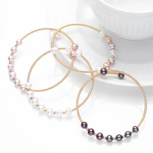 Detail of three 14K gold-filled spiral bracelets with pink, white, and purple pearls
