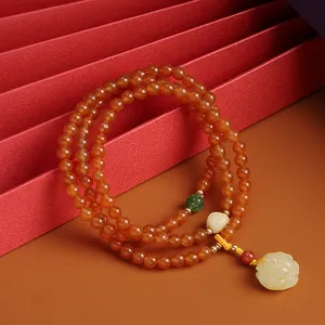 Detail of red agate beads bracelet with a yellow rose amber pendant on red paper