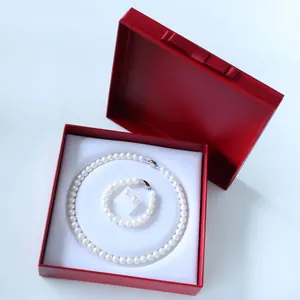 Detalle del conjunto de joyas de perlas blancas con collar en una caja de regalo roja