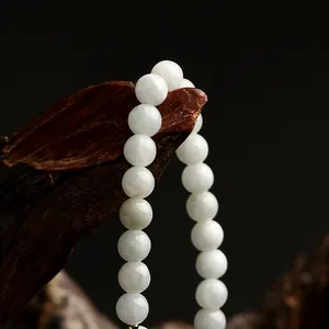 Macro shot of polished milky white jade beads hanging on dark wood with black background