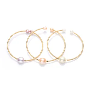 Detail of three 14K gold-filled wire bracelets with purple, champagne, and white pearls