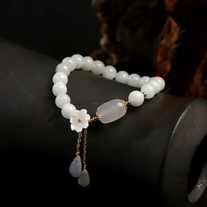 Detail of jadeite beaded bracelet with white shell flower and gold plated leaf charms