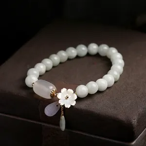 Macro shot of natural jade beads with a carved shell flower and 14K gold-filled charms