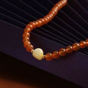 Macro view of cherry red agate beads with a carved yellow amber rose flower pendant