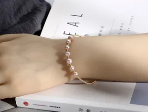 Detail of 14K gold-filled open cuff bracelet with eight lavender freshwater pearls on wrist