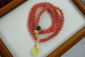 Detailed shot of multi-wrap red agate bracelet with amber rose charm and carved beads