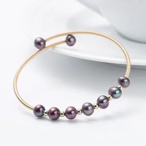 Detail of 14K gold filled bracelet with dark freshwater pearls on white surface