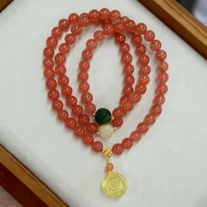 Macro shot of cherry red agate bead bracelet with a yellow amber rose flower pendant
