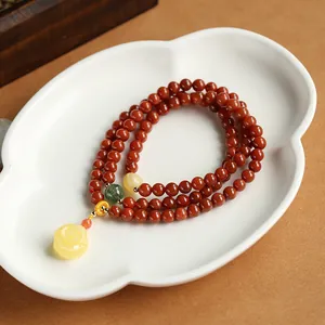 Macro shot of red agate beaded bracelet with a 14K gold honey wax rose pendant