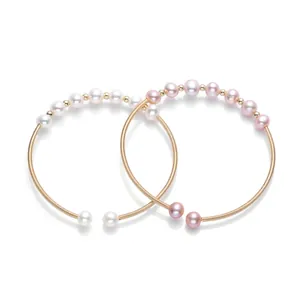 Detail of 14K gold filled open bracelets featuring white and pink freshwater pearls