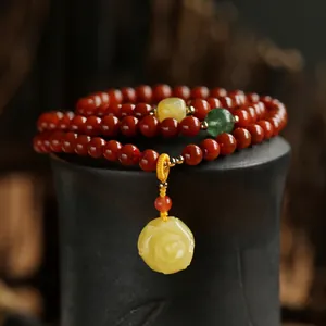 Detail of red agate bead bracelet with amber rose pendant and multi-color gems