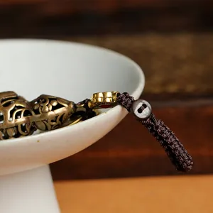 Macro shot of an antique brass hollow gourd pendant with detailed floral engraving and cord