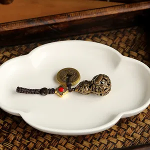 Detailed macro view of hollow brass gourd charm and antique coin on a braided brown cord