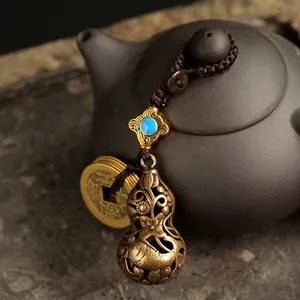 Macro shot of antique brass hollow gourd pendant with blue gemstone and vintage coins
