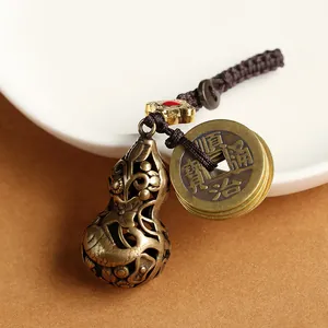 Detail of vintage brass hollow gourd keychain with ancient coins and koi relief