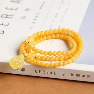 Three-layer amber beaded bracelet with carved Pixiu pendant on a minimalist magazine background