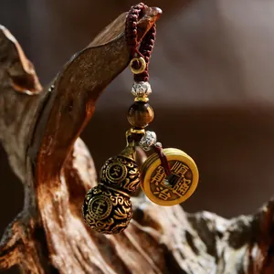 Brass gourd keychain with tiger eye stone and vintage coins on a rustic wood background