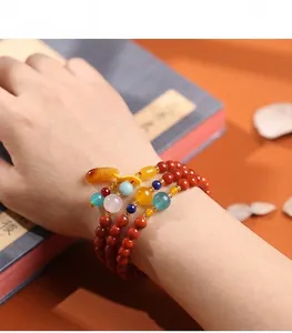 Macro-opname van meerlaagse rode agaat kralenarmband met barnsteen hanger aan de hand