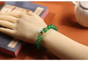 Detail of green agate beaded bracelet with jade gourd pendant on a traditional setting