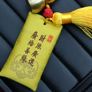 Makroaufnahme einer gelben chinesischen Stofftasche mit roter Stickerei und Goldkürbis