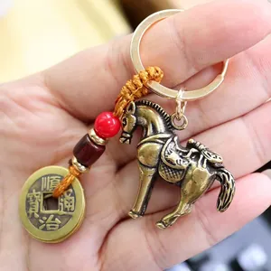 Macro detail of a brass horse charm and ancient coin keychain being held in hand