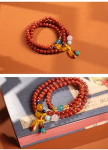 Detail van meerlaagse rode agaat kralenarmband met barnsteen hanger en kleurrijke accenten