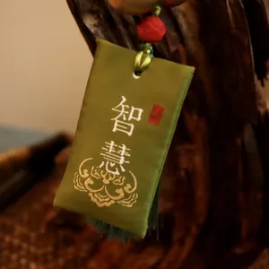 Traditionelles grünes chinesisches Sachet mit Weisheitsstickerei und roten Perlen auf Holz
