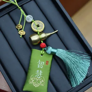 Detail eines grünen Seidensäckchens mit Messing-Kalebasse und Kupfermünze Deko