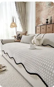 Detailed view of textured chenille sofa cover with scalloped edges and tassels