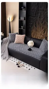 Close-up of quilted grey plush sofa covers and knot pillow on black leather sofa