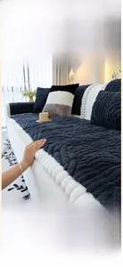 Détail de la housse de canapé en peluche gris foncé avec texture ondulée et pompons