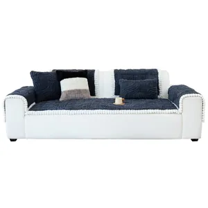 Housse de canapé en polaire jacquard bleu marine avec pompons blancs sur canapé blanc